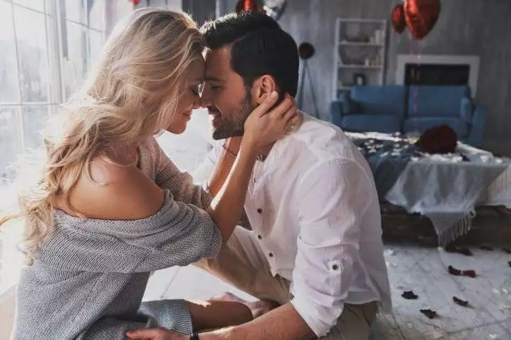Couple in love sitting closely together in their bedroom