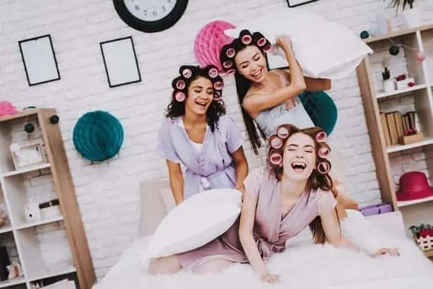Young cheerful friends in PJs having a pillow fight
