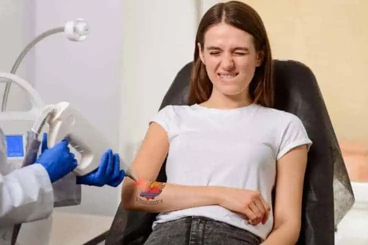 A young woman undergoing tattoo removal in pain