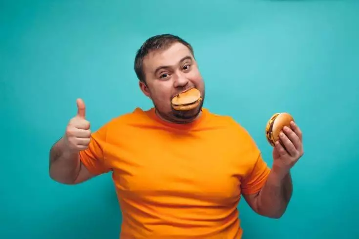 Man eating burgers because he loves food.