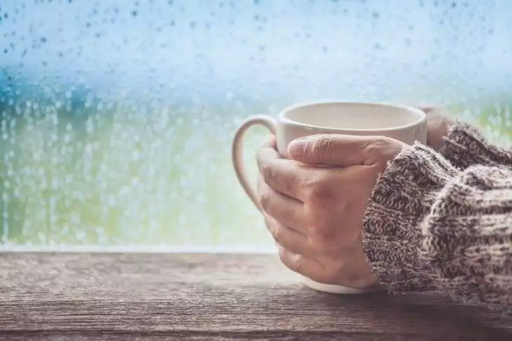 A girl drinking coffee or tea on a rainy day