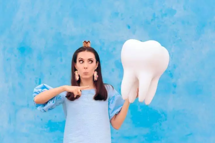 7 Reasons Why You Might Have Teeth Falling Out Dream 1 A woman holding a big tooth