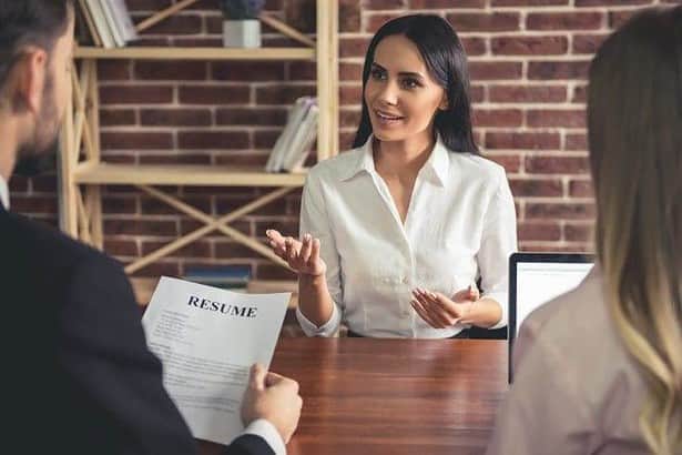 Man holding resume of the young woman and interviewing her