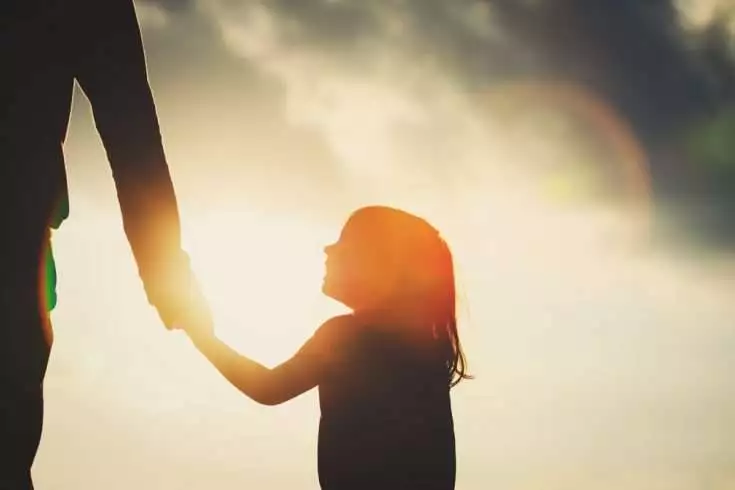Silhouette of a father holding his daughter's hand