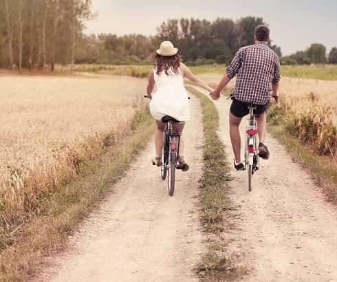 Couple in love riding bicycle while holding hands