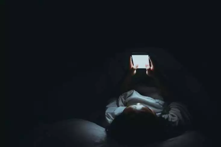 Woman using phone in darkness