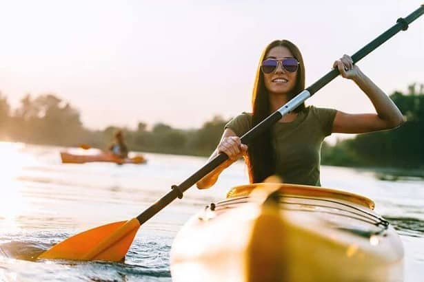 Nice day on kayak. Beautiful young smiling woman kayaking on river.