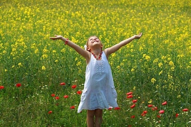 Pretty young girl happy to be surrounded by rapeseed flowers.