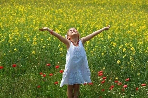 Pretty young girl happy to be surrounded by rapeseed flowers.