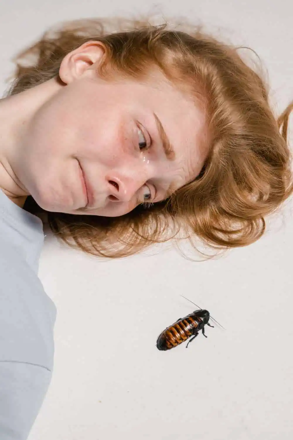 Fearful woman lying next to a roach