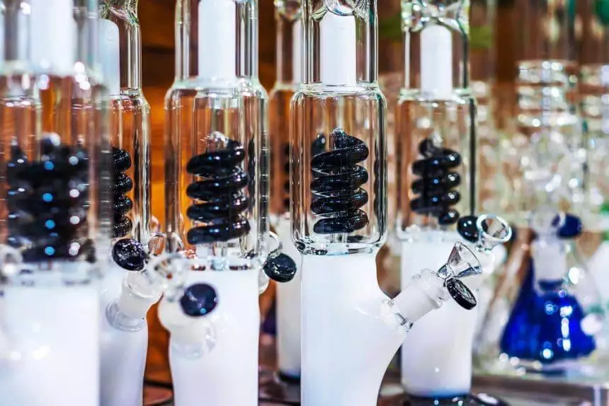 3 Reasons Why Your Bong Stinks & Easy Solutions 1 white bongs with black spiral percolator on blurred background.