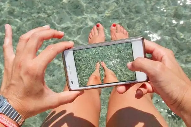 Young woman taking photos of her legs.