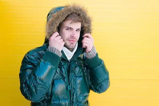 Staying stylish and cozy. Fashion model enjoying warmth and comfort. Casual fashion coat for cold winter conditions. Handsome man wearing faux fur hood. Fashionable man in cold weather style.