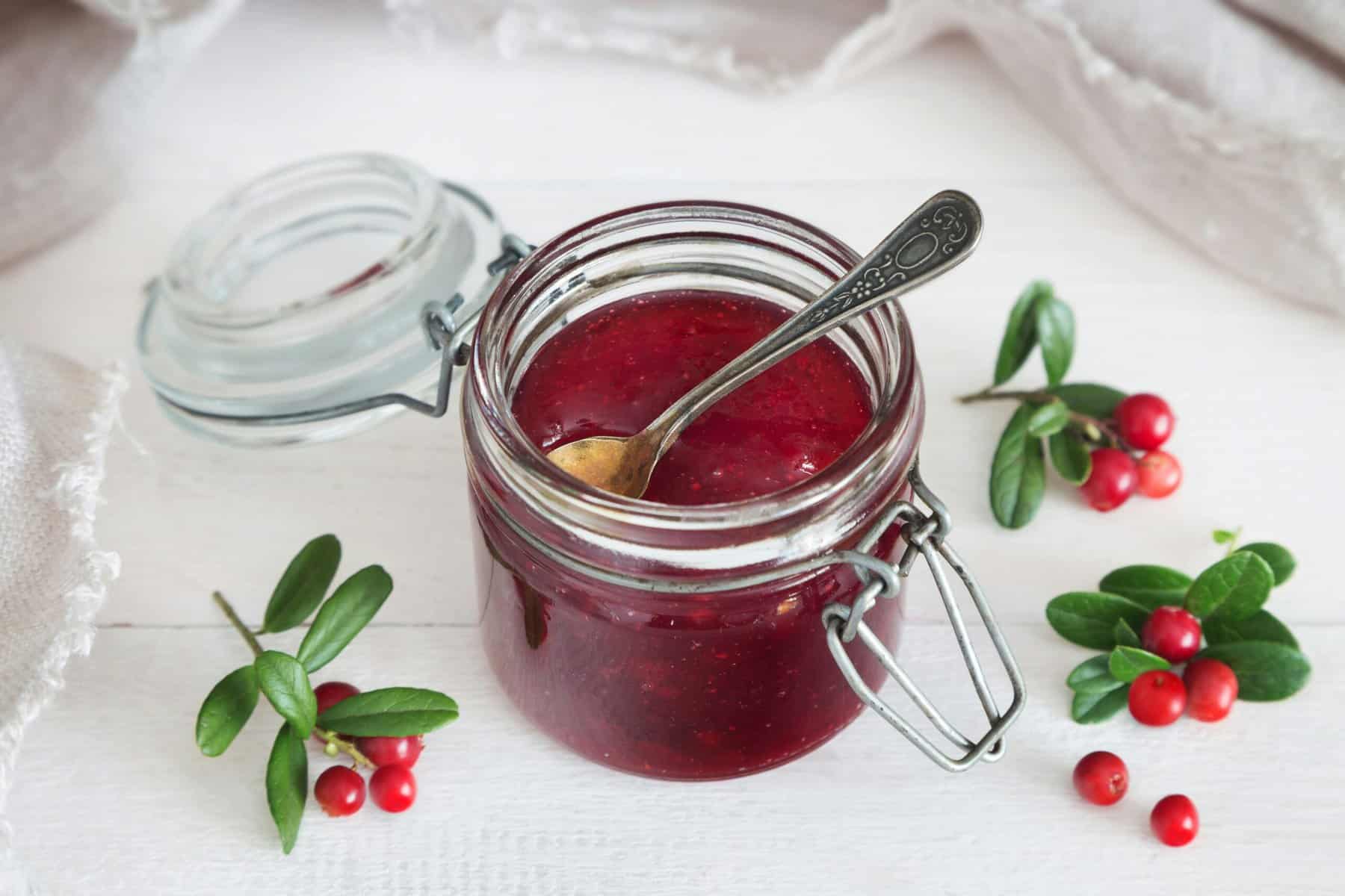 Homemade berry jelly in a glass jar with fresh berries