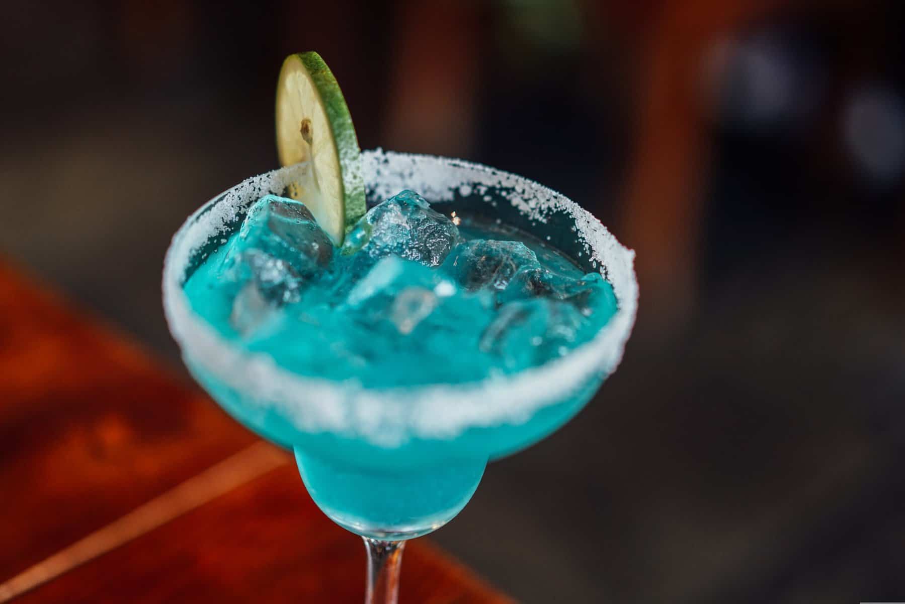 Blue Margarita cocktail with ice and lime wedge garnish, served in a salted rim glass.