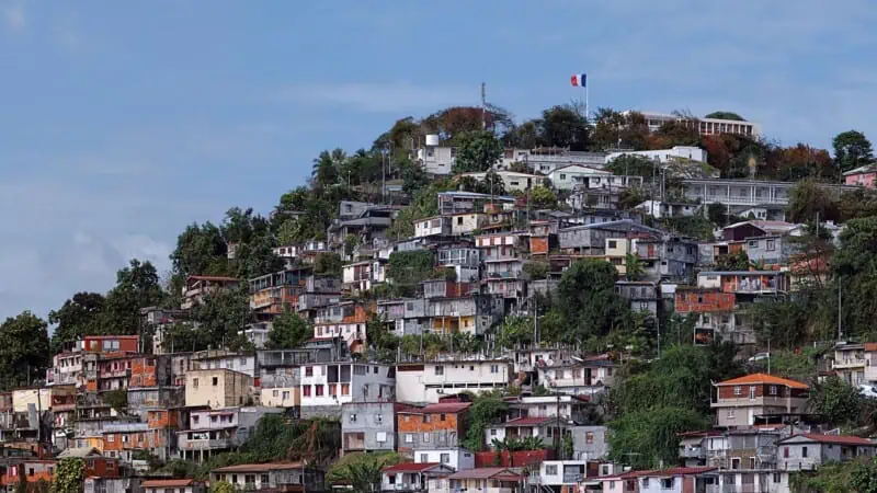 Hillside neighborhood with colorful houses and lush greenery on a hilltop.