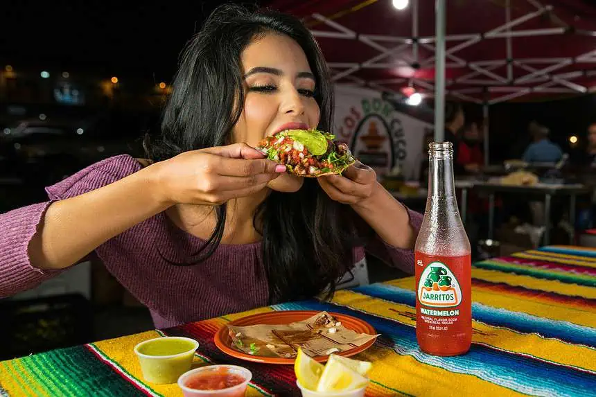 What To Do Instead Of Emotional Eating: Tips And Tricks 1 Woman enjoying a Mexican taco at a vibrant street food stall.