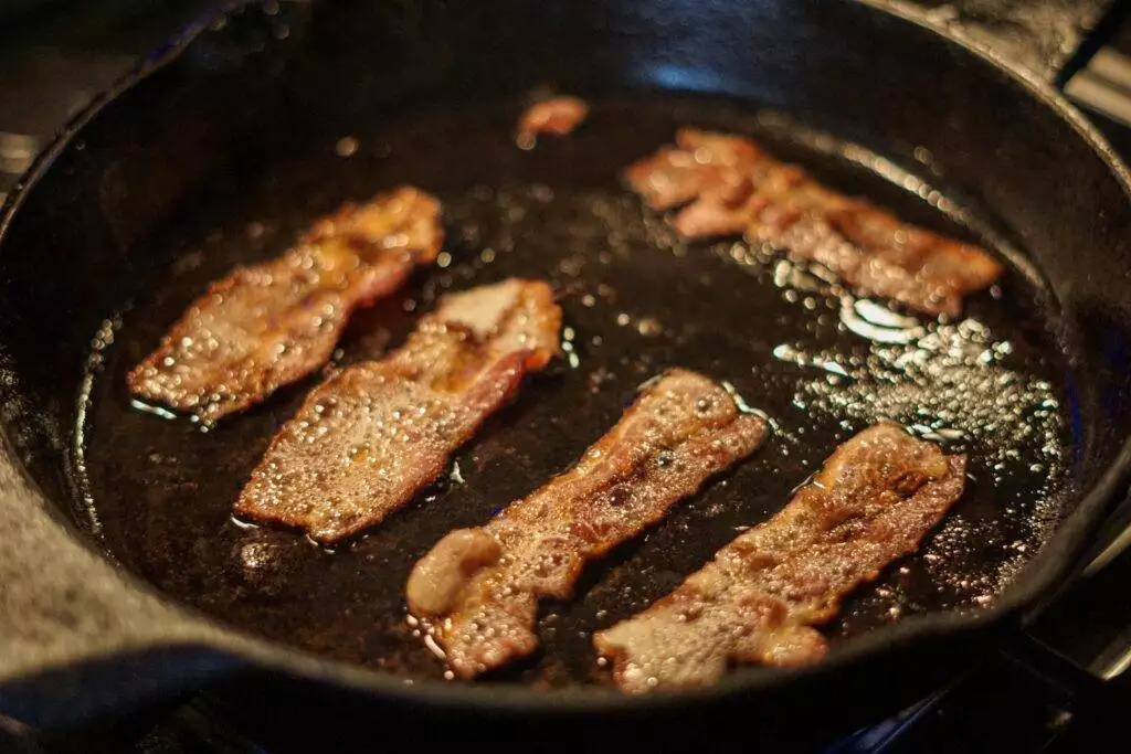 Bacon getting fried on a black pan