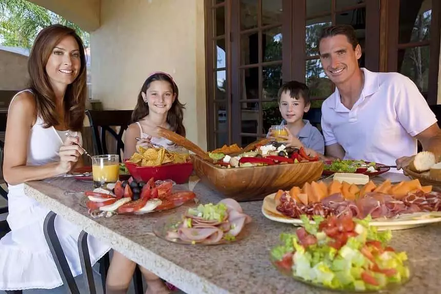 A happy family is eating their meal at a dining table at home.