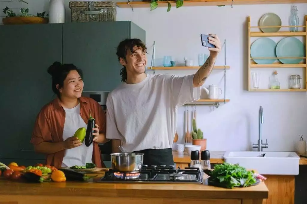 A couple taking selfie while cooking in the kitchen at home.