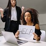 Woman holding help sign seeking support at work.