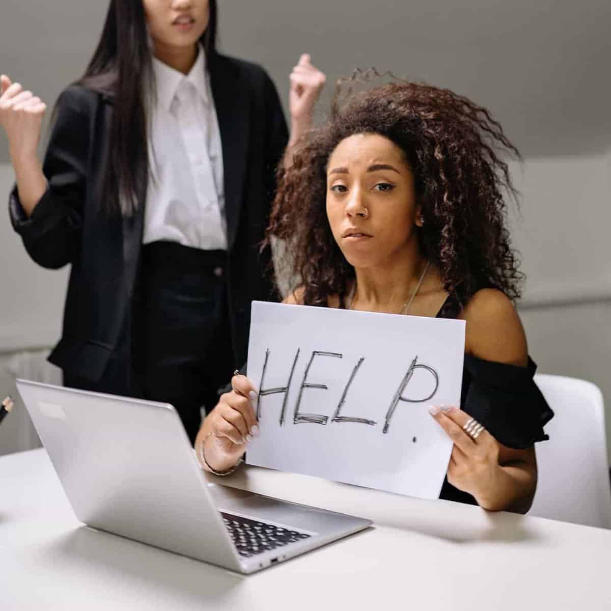 Woman holding help sign seeking support at work.