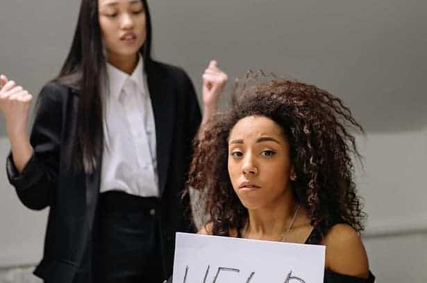 Woman holding help sign seeking support at work.