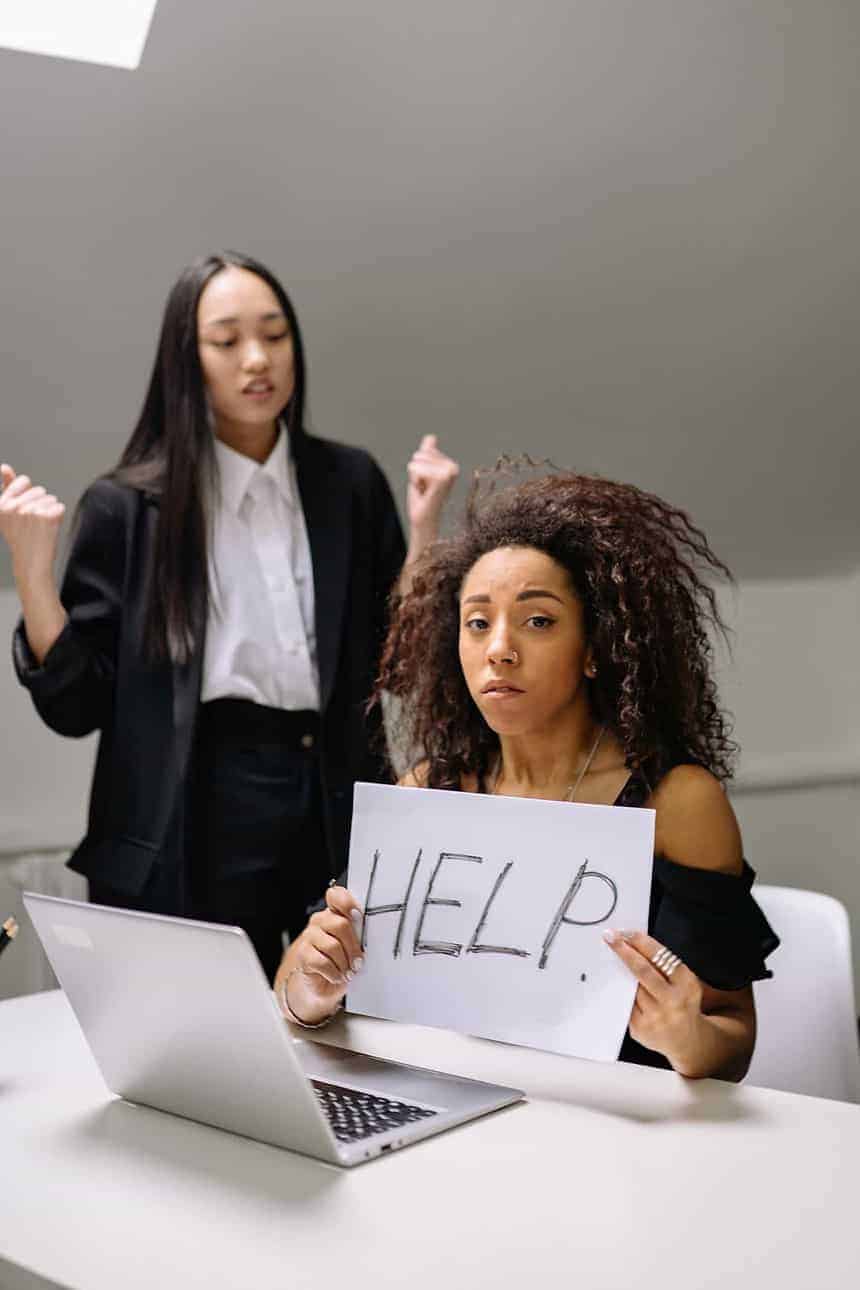 Woman holding help sign seeking support at work.