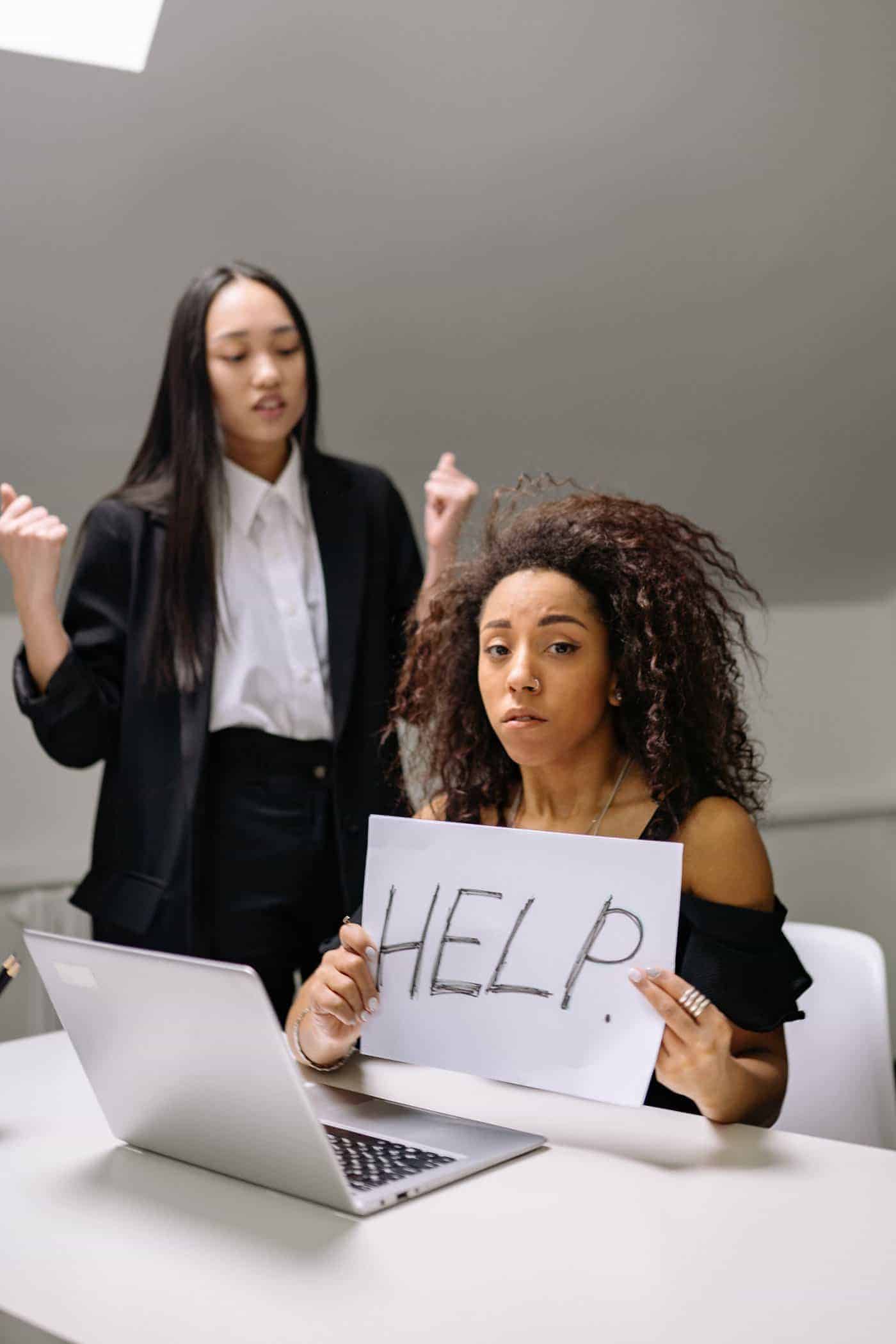 Woman holding help sign seeking support at work.