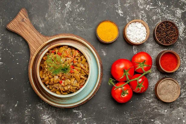 Delicious vegetable curry with tomatoes and spices on a dark surface.