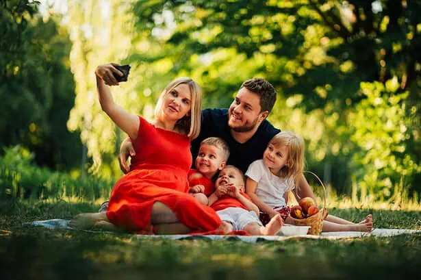 Family enjoying a picnic outdoors in a lush green park.