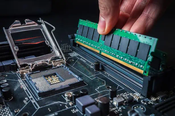 Computer motherboard with RAM modules being installed.