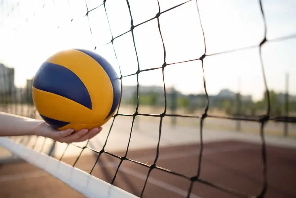 Volleyball hitting the net on an outdoor court during daytime.
