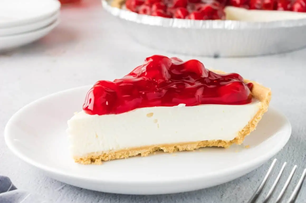 Slice of cherry cheesecake on white plate.