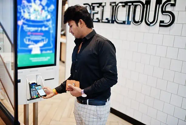 Man using contactless payment at self-service kiosk.