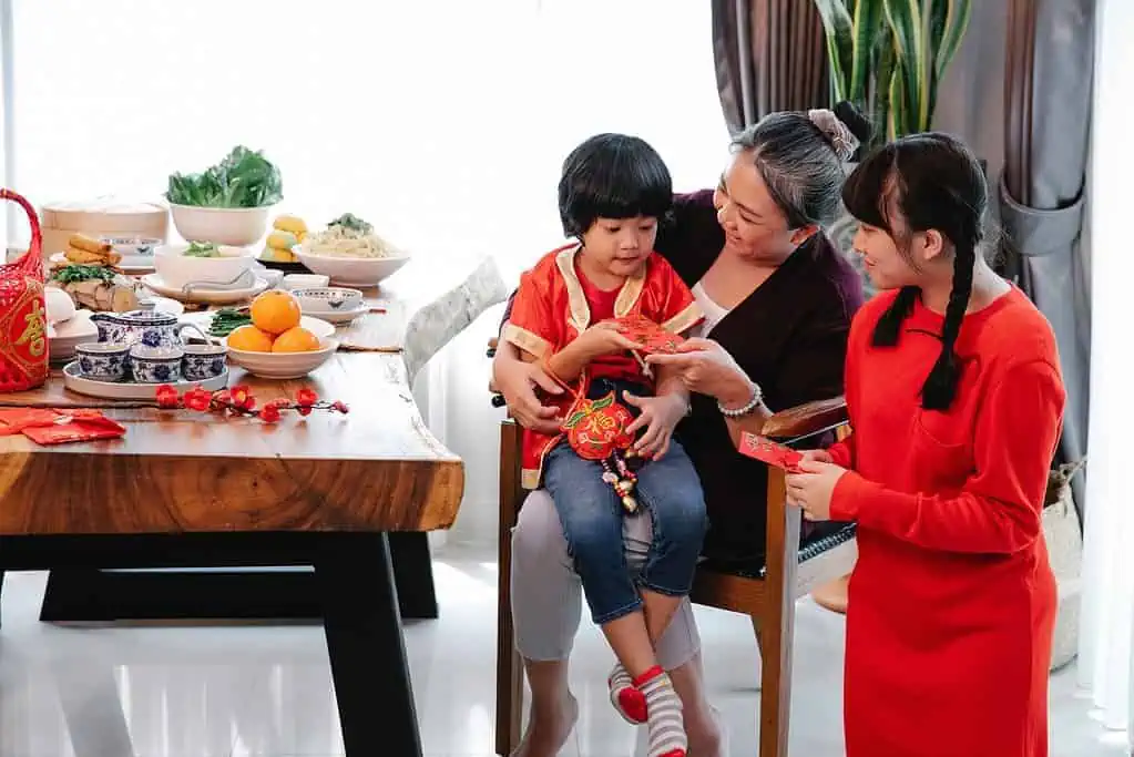 Smiling ethnic grandmother giving present to grandson
