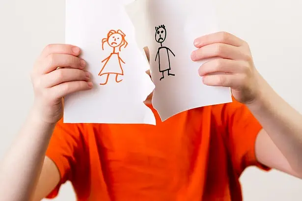 Child holding paper with drawings of a girl and boy, expressing emotions.