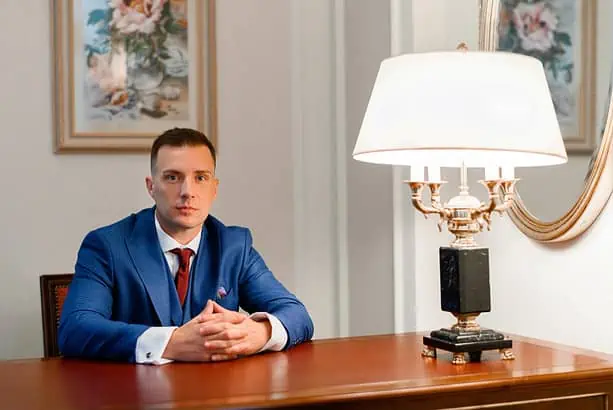 Businessman sitting at a desk in an elegant office setting with classic decor.