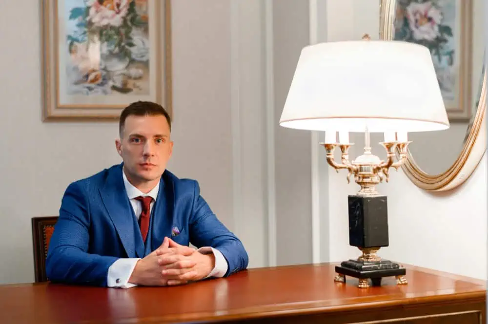 Businessman sitting at a desk in an elegant office setting with classic decor.