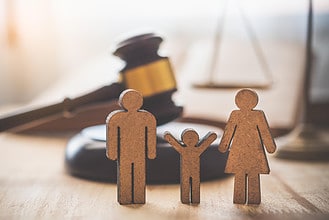 Legal family protection wooden figures with a gavel in the background, symbolizing family law and le.