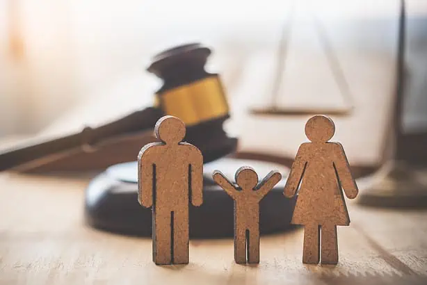 Legal family protection wooden figures with a gavel in the background, symbolizing family law and le.