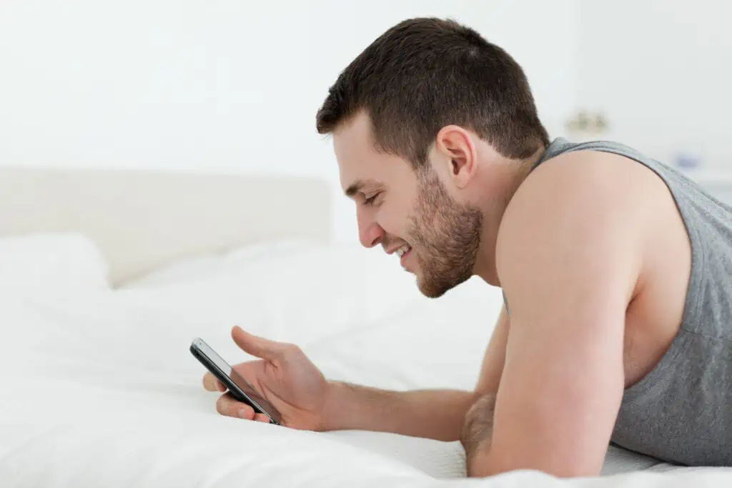 15 Ways to Keep Yourself Entertained on Your Mobile Phone When You're Bored 8 Man using his mobile phone in his bedroom