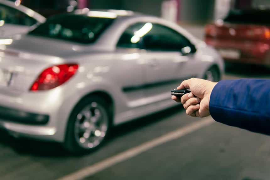 Man using key fob to lock car in underground parking lot