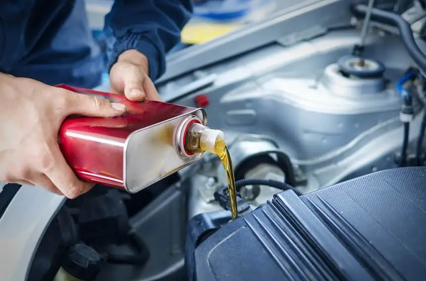 Engine oil being poured into a car engine during maintenance.