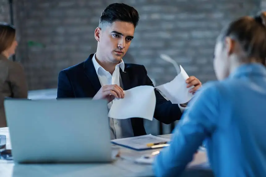 Manager critically reviewing reports with employee in office setting