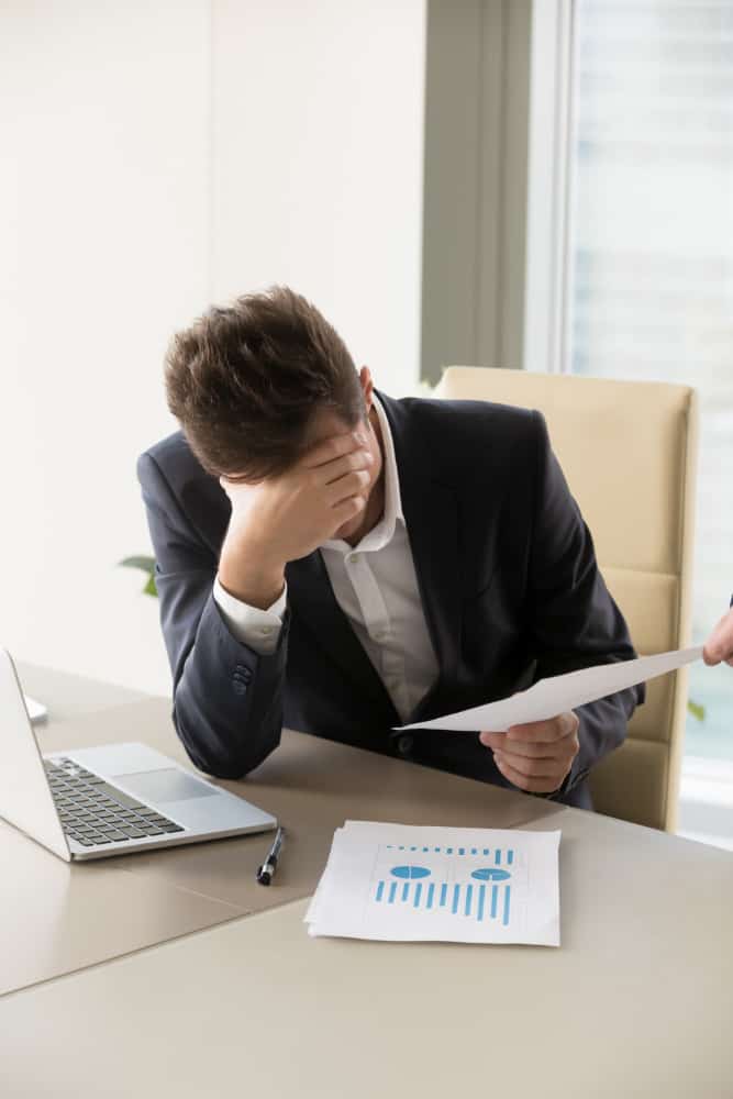 Stressed businessman with paperwork at office desk