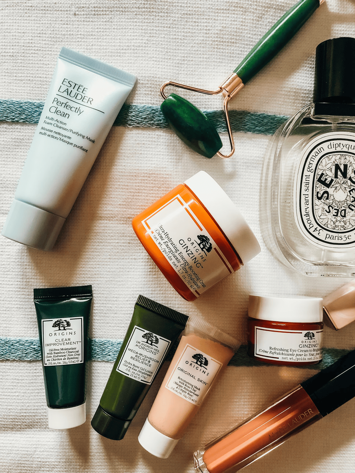 Assorted skincare products and jade roller on fabric