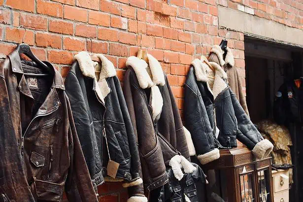 Vintage leather jackets on sale beside a brick wall.