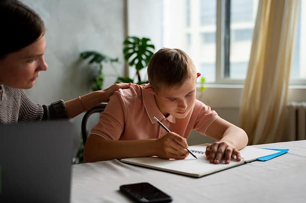 Mother helping son with homework at home.