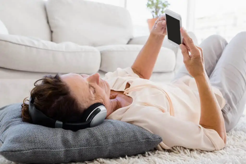 15 Ways to Keep Yourself Entertained on Your Mobile Phone When You're Bored 4 Mature woman using phone while listening to headphones at home